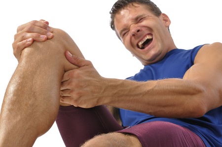 Male athlete on floor clutching knee and hamstring in excruciating pain on white background