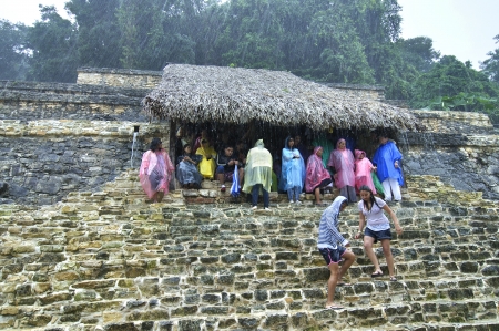 Palenque, Chiapas, Mexico - December 21, 2012: Heavy rains force visitors to seek shelter under a...