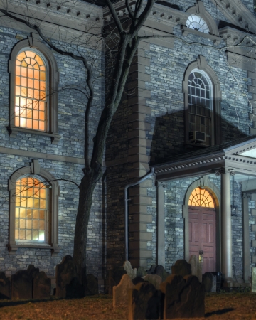 Exterior facade of scary haunted church with graveyard at nightの写真素材