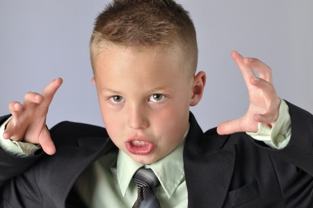 Closeup of young Caucasian boy in business suit making face and gesturing with hands as if he is going to attackの写真素材