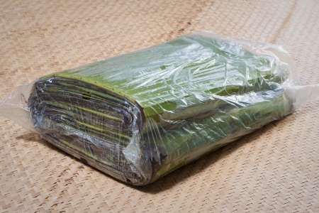Fresh banana leaves packed in clear plastic bag on palm matの写真素材