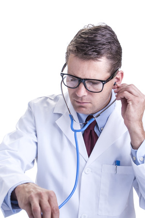Male Caucasian doctor in lab coat listens to unseen patient's heartbeat with stethoscope on white backgroundの写真素材