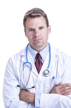 Portrait of serious handsome young Caucasian doctor in lab coat with arms crossed on white backgroundの写真素材