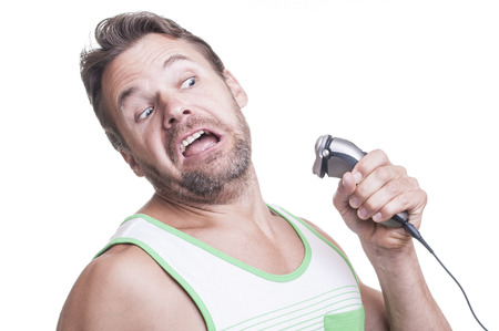 Scruffy Caucasian man ferociously fights back electric razor from reaching his bearded face on white  backgroundの写真素材