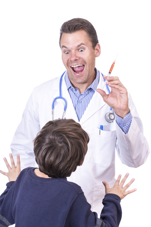 Child's fearful perception of crazy evil male doctor in white lab coat holding syringe filled with medicine on white backgroundの写真素材