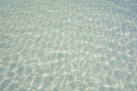 Water relfections on shallow sandy beach bottom of clear turquoise green lagoonの写真素材