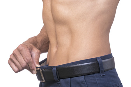 Torso of lean muscular Caucasian man pulling out belt line showing weightloss on white backgroundの写真素材