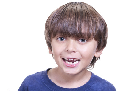Portrait of young boy smiling and showing his mouth full of loose baby teeth on white backgroundの写真素材