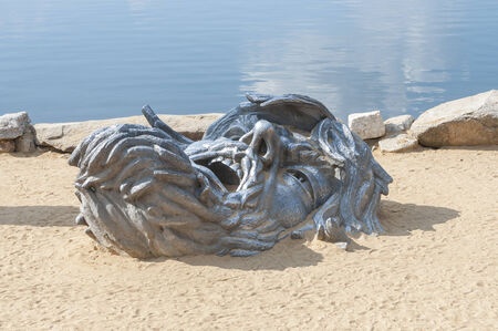 Giant head of the Awakening cast iron sculpture half buried in sand at National Harbor, Virginia の写真素材