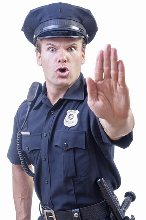 Male Caucasian police officer in blue cop uniform holds up hand in stop gesture on white backgroundの写真素材
