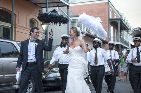 NEW ORLEANS, USA - OCTOBER 10, 2014: Newly wed bride and groom parade through the streets of the French Quarter in New Orleans followed by a jazz band in celebration of their union.のeditorial素材