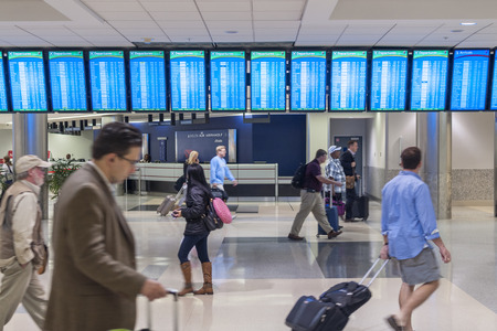 ATLANTA, USA - OCTOBER 14, 2014: Flight status monitors hang from the ceiling in the Atllanta International Airport as travelers hurry to catch their flights.のeditorial素材