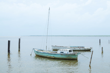 Two small old rustic sailboats docked in Chetumal Bay in Chetumal, Mexicoのeditorial素材