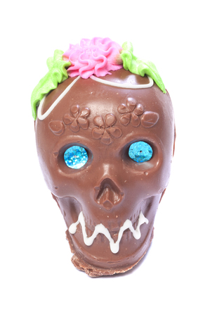 Closeup of chocolate candy skull with bead eyes and colored frosting on white background to celebrate Day of the Deadの写真素材