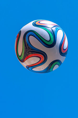 Colorful World Cup soccer ball flying in air with clear blue sky background