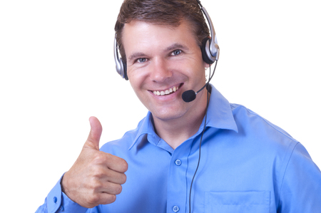 Closeup portrait of handsome smiling Caucasian man wearing blue collared shirt and communications headset giving thumbs up on white backgroundの写真素材
