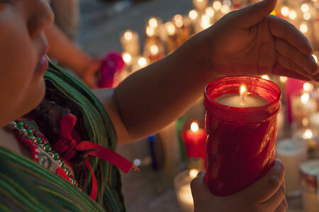 LAS CHOAPAS, MEXICO - DECEMBER 12, 2014: A young girl in traditional dress shields the flame of a candle after mass commemorating Our Lady of Guadalupeのeditorial素材
