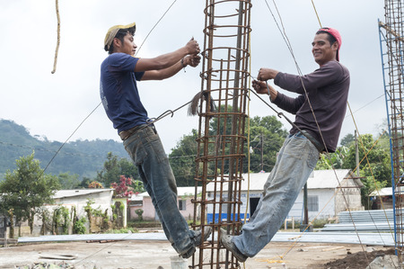 CHAPULTENANGO, CHIAPAS, MEXICO - DECEMBER 19, 2014: Two young men work diligently tying rebar together to prepare a column for pouring concrete in Chapultenango, Chiapasのeditorial素材