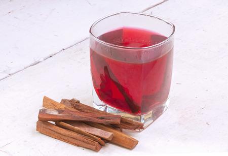 Small stack of pieces and glass of red tea of Haematoxylum brasiletto Mexican logwood on white tableの写真素材