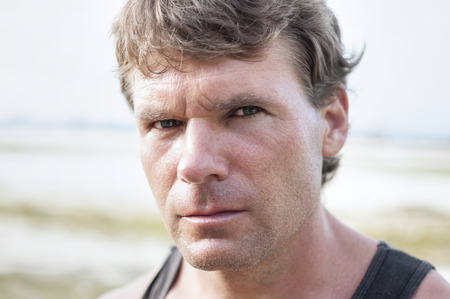Closeup portrait of rugged Caucasian man with stern bold facial expression, distinct features, and intense predator eyes in undefined outdoor environmentの写真素材