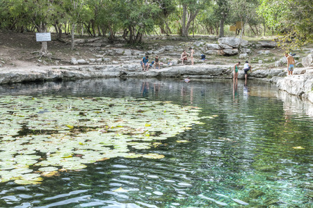 MERIDA, MEXICO - JANUARY 19, 2015: Tourists gather at the loal water hole, the beautiful Xlacah cenote at the Maya ruins site of Dzibilchaltun near Merida, Yucatanのeditorial素材