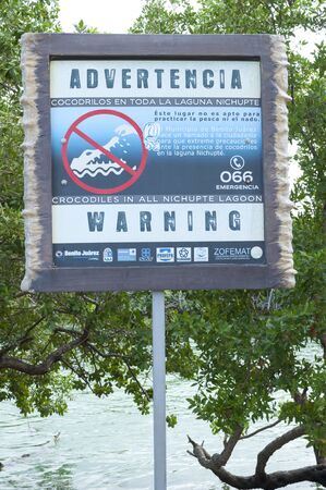 CANCUN, MEXICO - JANUARY 22, 2015: A sign is posted on the shore of the Nichupte Lagoon in Cancun warning of the presence of dangerous crocodiles throughout the lagoonのeditorial素材