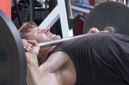Closeup of Caucasian man performing high bench press with heavy barbellの写真素材