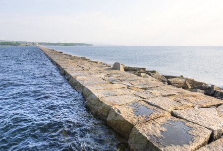 Rocky breakwater jetty extends for seveneighths of a mile from shore to middle of bay in Rockland Maineの写真素材