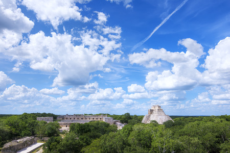 Beautiful scenic landscape of ancient Maya city Uxmal with Pyramid of the Magician and the Nunnery clearly visible as they rise up from the green jungle under a sunny skyの写真素材