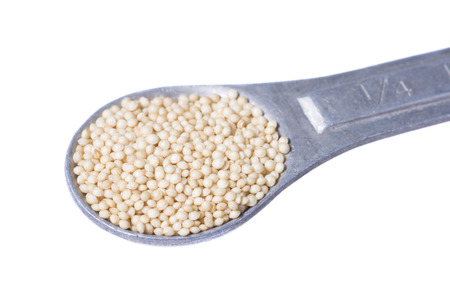 Macro closeup of quarter teaspoon measurement of raw amaranth seed on white backgroundの写真素材