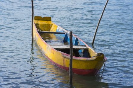 Colorful rustic canoe half-filled with water tied to stick poles in Riacho Breiao river near Maceio, Alagoas, Brazilの写真素材