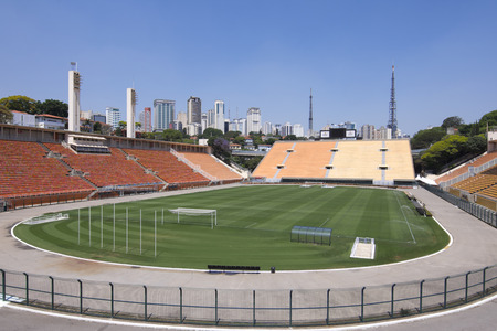 SAO PAULO, BRAZIL - SEPTEMBER 23, 2015: Empty stands and green turf of the football field sit below a sunny blue sky and the skyline of tall skyscrapers of Sao Paulo at Paceambu Stadium Estdio Municipal Paulo Machado de Carvalho.のeditorial素材