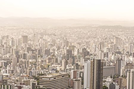 Tall concrete buildings sprawl through heavily urbanized valley in Belo Horizonte, Minas Gerais, Brazil under hazy skyの写真素材