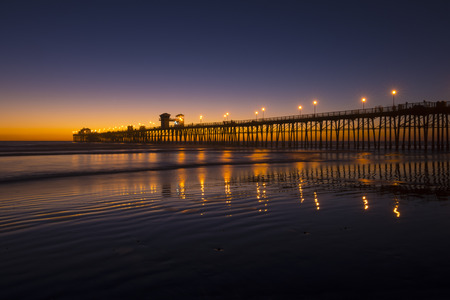 Magnificent vivid dusk sky after sunset on beautiful sandy beach with long pier in Oceanside, California on October 30, 2015の写真素材