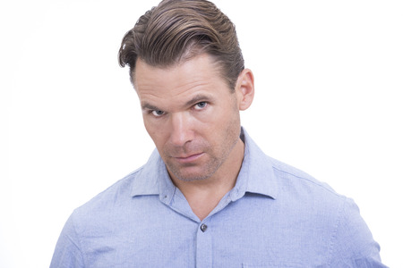 Portrait of handsome Caucasian man with head tilted slightly down looking up at camera with blank expression on white backgroundの写真素材