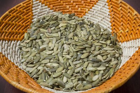 Closeup colorful native American handmade basket full of raw green pumpkin seedsの写真素材
