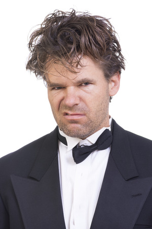 Portrait of mad deranged Caucasian man with long messy hair wearing messed up black tuxedo on white backgroundの写真素材