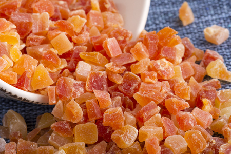 Closeup spilled bowl of dehydrated diced Carica papaya cubes on blue fabric placematの写真素材