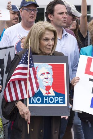 SAN DIEGO, USA - MAY 27, 2016: A woman peacefully protests Donald Trump's presidential campaign by holding an American flag with a "No Hope" sign featuring Trump's photo outside a Trump rally.のeditorial素材
