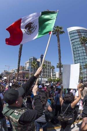 SAN DIEGO, USA - MAY 27, 2016: A man waves the Mexican national flag high over head before a crowd protesting the Trump campaign outside the San Diego Convention Centerのeditorial素材