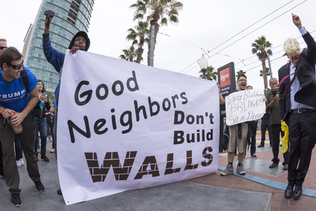 SAN DIEGO, USA - MAY 27, 2016: Anti-Trump protesters display their opinion about the wall while a Trump fan smiles at their efforts during a protest outside a Trump rally in San Diego.のeditorial素材