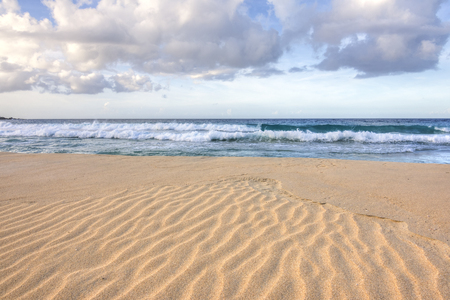 Wide angle closeup of ripples in coarse orange sand as waves roll into shore on Playa Brava on Isla Culebra in Caribbean Sea under diffused natural lightの写真素材