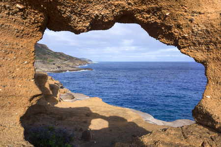 Pacific Ocean and Lanai lookout on rocky southeast coast of Oahu through natural earth windowの写真素材