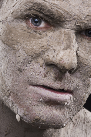 Macro closeup scary face of man with dry flakes of cracked mud covering his skin like a mummified corpseの写真素材
