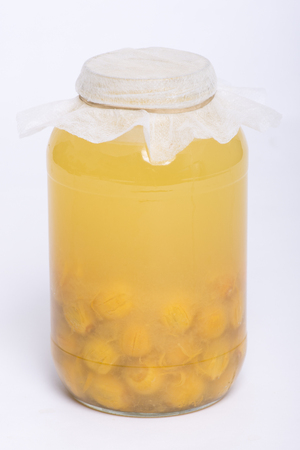 Queen palm fruits fermenting in glass jar making natural pro-biotic beverage on white backgroundの写真素材