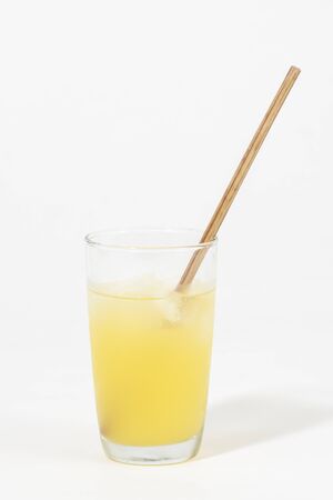 Natural juice beverage in glass with wooden straw on white backgroundの写真素材