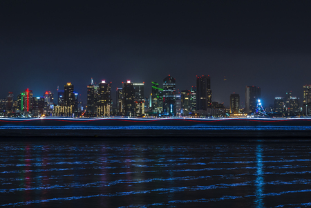Wide angle San Diego skyline over bay with trailing boat lights and reflections over water from long exposureのeditorial素材