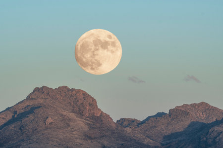 Full moon rising over rugged desert mountains in Arizonaの写真素材