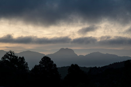 Silhouette of desert mountain landscape with drifting grey clouds at dawnの写真素材