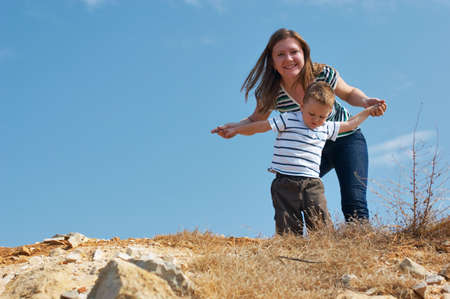 We can fly. Mother and son playing outdoors on top of hill at sunny dayの写真素材
